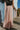Back view of model wearing the Melrose Avenue Pleated Pants that have blush-colored pleated fabric, blush lining, an elastic waistband, and wide legs