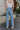 Back view of model wearing the Step Up Wide Leg Jeans which features medium wash denim fabric, a front zipper with button closure, two front pockets, two back pockets, distressed detailing, and wide legs.