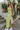 Full body view of model wearing the To The Keys Midi Dress which features lime green knit fabric with a maxi length hem, a side slit, lime green lining, a strapless neckline with folded trim, and a cut out back with button closures.