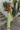 Side view of model wearing the To The Keys Midi Dress which features lime green knit fabric with a maxi length hem, a side slit, lime green lining, a strapless neckline with folded trim, and a cut out back with button closures.