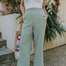Front view of model wearing the Good Luck Pants that have light sage gauze fabric, front pockets, a raw hem, and an elastic waistband