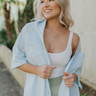 Front view of model wearing the Weekend Wishing Top in Blue which features light blue fabric, monochromatic buttons, a collared neckline, and short sleeves.