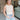 Front view of model wearing the Call It Even Bodysuit in Nude that has stretchy nude fabric, a round neckline, a sleeveless design, and a thong bottom with snap closures.
