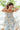 Front view of model wearing the Hello Sunshine Top that has purple, blue, orange, green, yellow and ivory fabric with a floral pattern, a peplum hem, a smocked upper, a square neckline and tie straps.