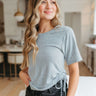 Front view of model wearing the Days Go By Ruched Top that features heather grey knit fabric, a round neckline, short sleeves, and ruching ties on each side.