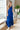 Full body front view of model wearing the Across the Ocean Maxi Dress that has royal blue fabric, maxi length, a ruffle tiered body, a tie around the waist, a smocked upper, one shoulder strap, and royal blue lining.