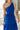 Upper front view of model wearing the Across the Ocean Maxi Dress that has royal blue fabric, maxi length, a ruffle tiered body, a tie around the waist, a smocked upper, one shoulder strap, and royal blue lining.