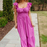 Front view of model wearing the Love Like Ours Midi Dress that has orchid pink textured fabric, midi length, a ruffle tiered hem, a smocked waistband, a square neckline with ruffle trim, ruffle straps, an open back, and a drawstring tie closure