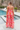 Full body back view of model wearing the Make Bold Moves Jumpsuit features orange, pink, red, purple and turquoise pleated fabric with a marble pattern, a smocked chest with ruffle trim, tie spaghetti straps, and peach lining.