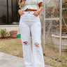 Front view of model wearing the Kancan: Where It Ends Jeans which features white denim fabric, two front pockets, two back pockets, front zipper with button closure, distressed details and wide pant leg.
