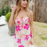 Front body view of model wearing the Malibu Mini Dress which features hot pink, peach, green, light pink and white fabric with a floral pattern, mini length, a pleated wire upper, a sweetheart neckline, tie straps, and an open back with a tie and hook clo