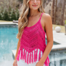 Front view of model wearing the Destination Location Tank which features hot pink crochet fabric, a tasseled hem, a v-neckline, and spaghetti straps.