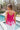 Back view of model wearing the Destination Location Tank which features hot pink crochet fabric, a tasseled hem, a v-neckline, and spaghetti straps.