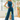 Full body view of model wearing the Ready To Go Denim Jumpsuit in Indigo which features indigo denim fabric, waistband, high round neckline, sleeveless, back zipper closure and flare pant leg.