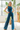 Full body view of model wearing the Ready To Go Denim Jumpsuit in Indigo which features indigo denim fabric, waistband, high round neckline, sleeveless, back zipper closure and flare pant leg.