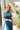 Close up front view of model wearing the Ready To Go Denim Jumpsuit in Indigo which features indigo denim fabric, waistband, high round neckline, sleeveless, back zipper closure and flare pant leg.