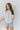 Front view of model wearing the All For You Top that has white cotton fabric, a scooped hem, a smocked upper chest, a round neckline and short flare sleeves