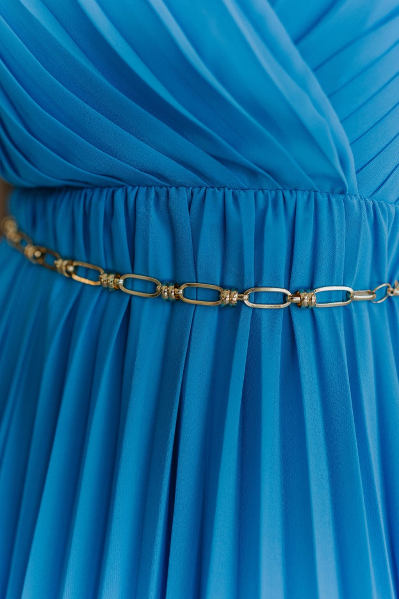 Close up view of model wearing the Chain Reaction Link Belt which features gold open chains linked together with links and hook clasp closure.