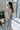Side view of model wearing the Better This Way Dress which features light blue, dark blue and cream brocade fabric with a floral design, a midi-length hem, a front slit, a straight strapless neckline, and a monochromatic back zipper.
