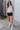 Full body view of model wearing the Rolling Stones Shorts which features black denim fabric, silver stud details on the side, a front zipper and button closure, belt loops, two front pockets, two back pockets and a frayed hem.