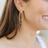 Side view of model wearing the Stay Golden Earring which features three gold slinky circles linked with a gold rectangle stud.