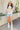Full body front view of model wearing the Nashville Graphic Tee that has cream fabric, a round, and short sleeves. Graphic says Music City and Nashville, TN with pink roses, light blue leaves and a guitar outlined in brown