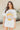 Front view of model wearing the Nashville Graphic Tee that has cream fabric, a round, and short sleeves. Graphic says Music City and Nashville, TN with pink roses, light blue leaves and a guitar outlined in brown