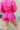 Back view of model wearing the Star-Struck Skort that has fuchsia nylon fabric, multi-colored sequin star patches, fuchsia shorts lining, and a high-rise smocked waistband