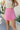 Front view of model wearing the Stepping Out Skort in Pink that has pink fabric with a slit detail, pink shorts lining, a wood button, and a monochromatic side zipper with a hook closure