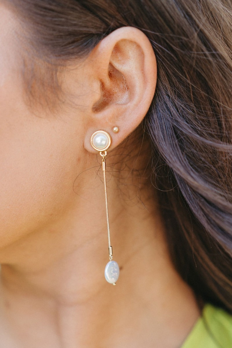 Close up view of model wearing the Radiant Pearl Earring which features pearls set in gold and linked to another pearl with gold attachments.
