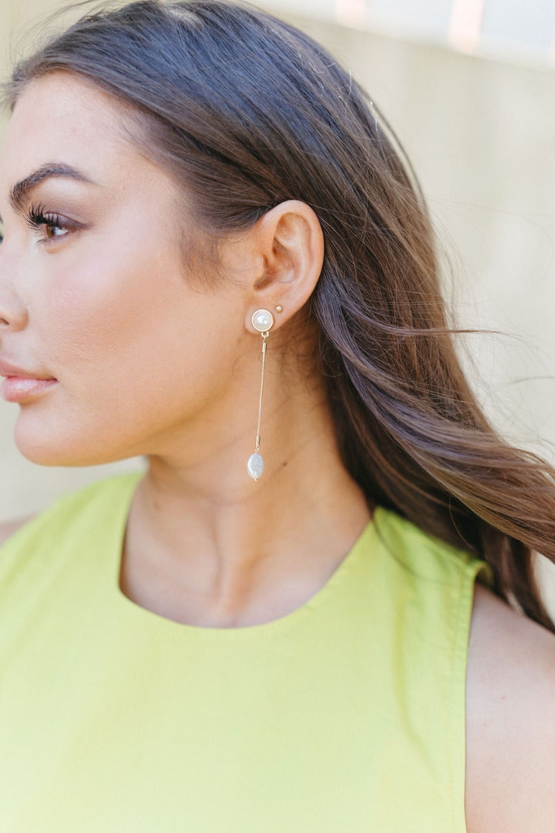 Side view of model wearing the Radiant Pearl Earring which features pearls set in gold and linked to another pearl with gold attachments.