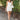 Full body front view of model wearing the Happiest With You Romper that has white denim fabric, a scooped skirt design with ruched detailing on the side, white shorts lining, a strapless sweetheart neck, and a back zipper with hook closure