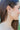 Side view of model wearing the Paint The Town Earring which is a hoop style earring, featuring a small white hoop with gold dots through out.