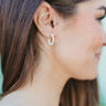 Side view of model wearing the Paint The Town Earring which is a hoop style earring, featuring a small white hoop with gold dots through out.