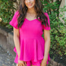 Front view of model wearing the Wishful Thinking Romper which features fuchsia fabric, a ruffle-tiered skirt, fuchsia shorts lining, an elastic waistband, a sweetheart neckline and short puff sleeves.