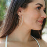 Close up side view of model wearing the On Your Own Hoop Earrings in Silver which features large closed hoop with silver hammered design.