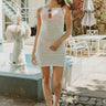 Full body front view of model wearing the White Sands Cover Up that has ivory open knit fabric, a mini-length hem, a square neckline and spaghetti straps.