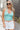 Front view of model wearing the Chasing Summer Tank in Mint which features mint green knit fabric, a cropped waist, a halter neckline, an open back and a sleeveless design.