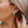 Side view of model wearing the Checkmate Earring in Mint which features turquoise and mint square beads, checkered design and mini open hoops with gold details.