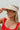 Front view of model wearing the Rida Straw Visor that has ivory woven material with a geometric design and an elastic band.