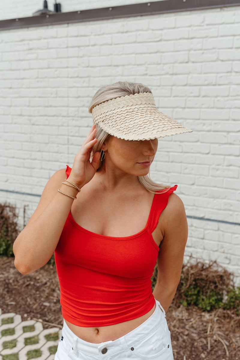 Front view of model wearing the Rida Straw Visor that has ivory woven material with a geometric design and an elastic band.
