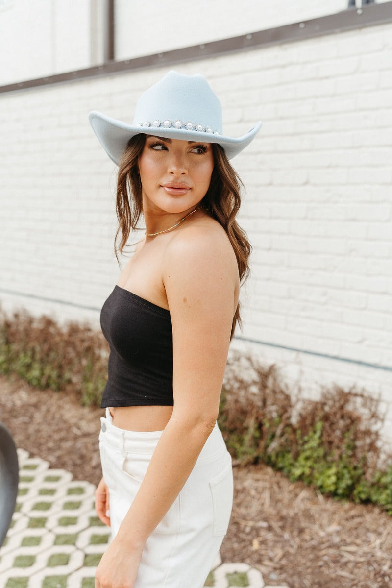 Side view of model wearing the Do Not Disturb Tube Top which features black fabric, a cropped waist, and a strapless neckline.