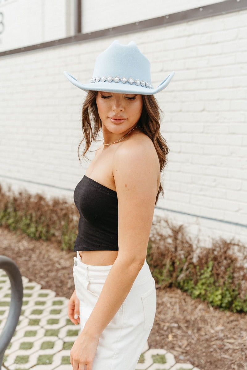 Side view of model wearing the Do Not Disturb Tube Top which features black fabric, a cropped waist, and a strapless neckline.