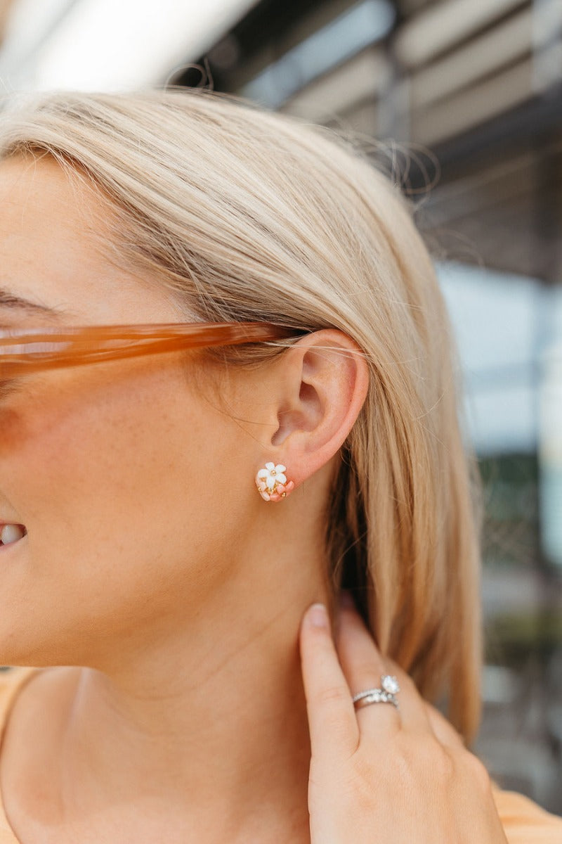 Side view of model wearing the Cluster of Flower Earring which features gold studs with pink, light pink and white flowers.