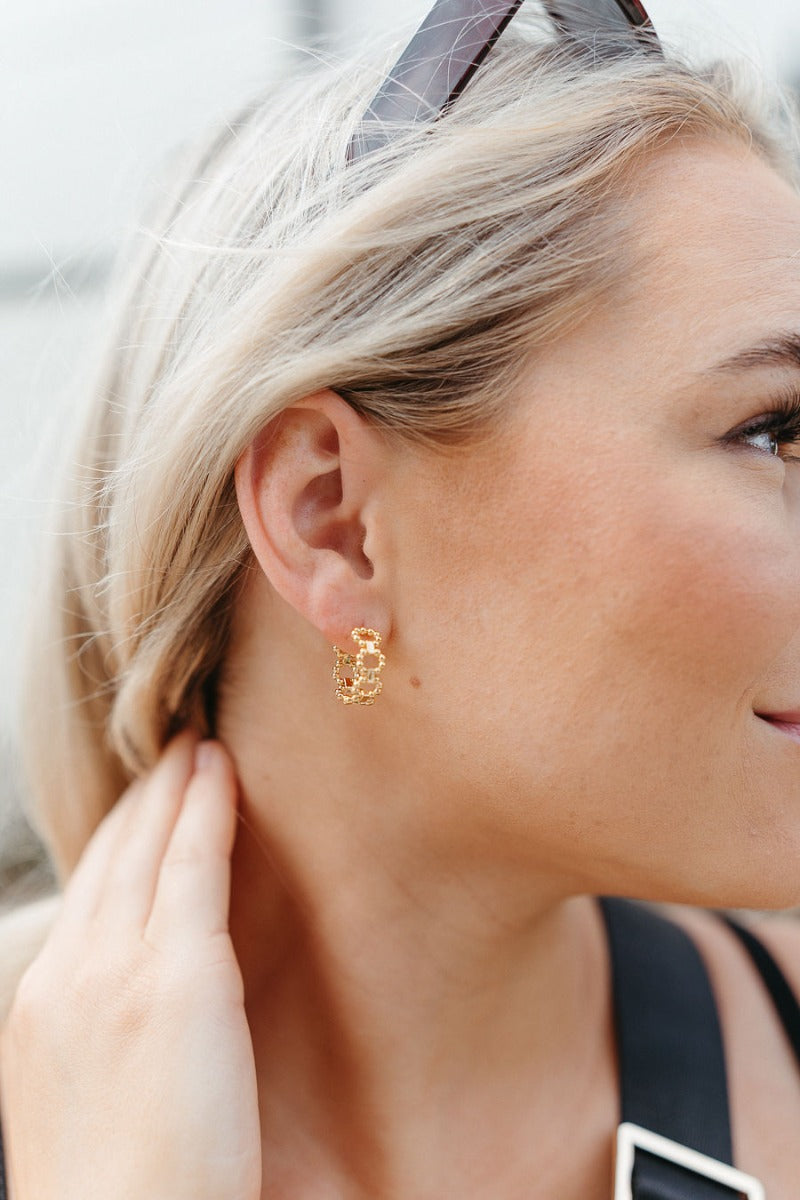 Side view of model wearing the On The Dot Mini Hoop Earring which features mini gold closed hoops shaped with gold mini beads.