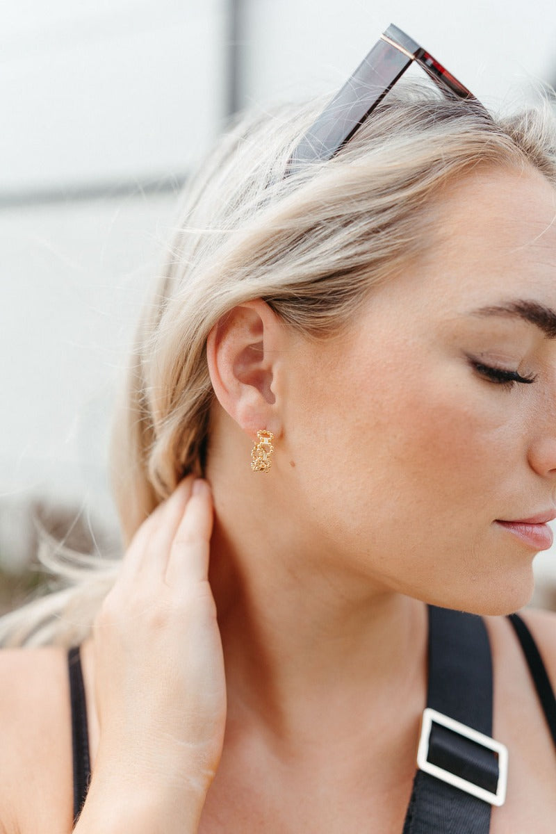 Side view of model wearing the On The Dot Mini Hoop Earring which features mini gold closed hoops shaped with gold mini beads.