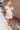 Full body view of model wearing the You Found My Heart Dress which features light pink textured fabric with a monochromatic embroidered floral print, light pink lining, baby doll style, a scooped neckline, short puff sleeves, an open back with a tie closu
