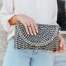 Model is holding the Ready For Sunshine Straw Purse that has black and ivory woven fabric with a geometric pattern, a cognac faux-leather strap, gold hardware, black interior lining, and a snap closure.