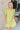 Front view of model wearing the Sweet Escape Ruffle Dress which features lime green fabric, a two-tiered body, pockets on each side, mini length, lime green lining, a square neckline, smocked details, and short ruffle sleeves.
