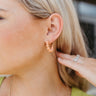 Side view of model wearing the Peachy Queen Earring which features small open hoops with peach bubble design.